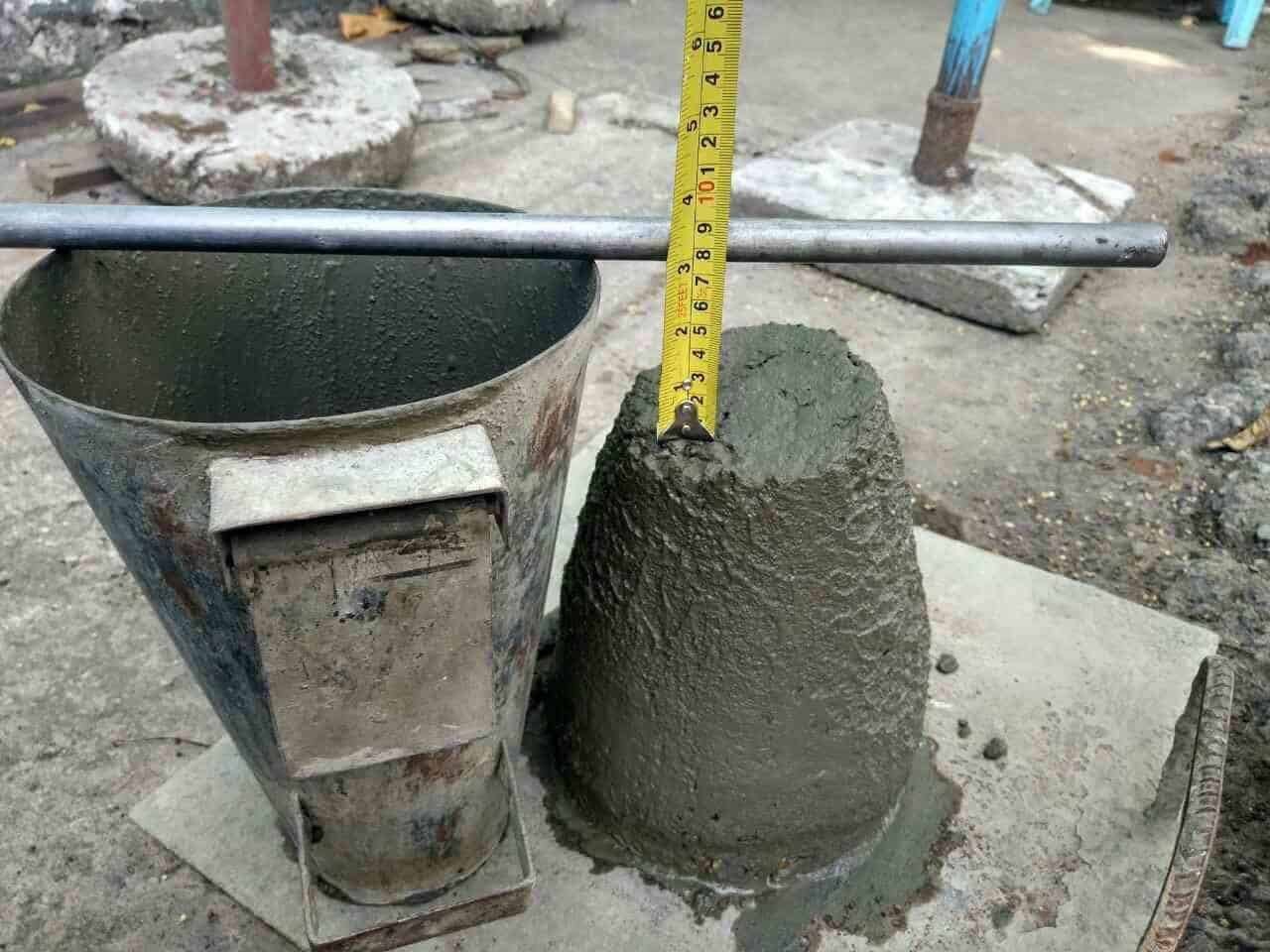 کارگران در حال اندازه‌گیری عیار بتن با دستگاه اسلمپ در یک پروژه ساختمانی